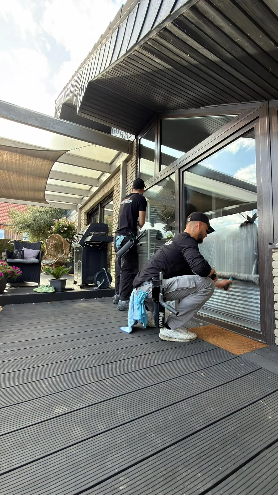 Zwei Mitarbeiter reinigen die Glasfront an einer Terrasse